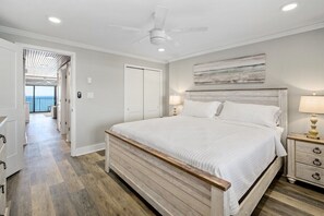Ein Schlafzimmer mit einem hölzernen Bett, weißen Wänden, einem Deckenventilator und Blick auf einen Balkon.