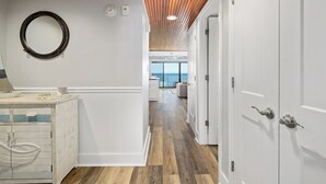 A hallway with white doors, a wooden ceiling, and a view to a balcony. - Oceanfront 1 Bedroom, Balcony, Sitting Room, Pool (Ocean City)