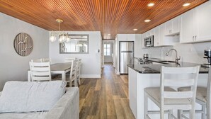 A modern kitchen with white cabinets, a stainless steel refrigerator, and a wooden ceiling. - Oceanfront 1 Bedroom, Balcony, Sitting Room, Pool (Ocean City)