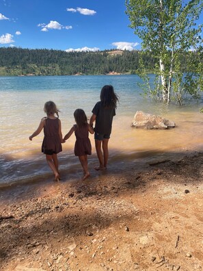 Un paysage naturel comprenant un lac, des arbres et une rive rocheuse.