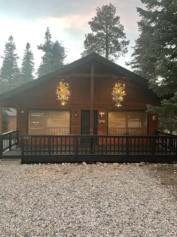 Un chalet avec une façade en bois, une véranda et une allée gravillonnée.
