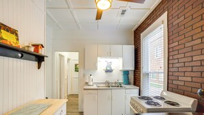 A kitchen with white cabinets, a stove, and a window with blinds. - Quaint Mt Vernon Cottage Near Historic Dtwn! (Mt Vernon)