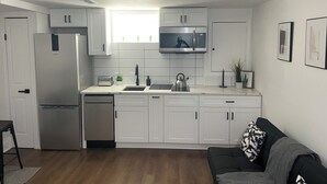 Una cocina moderna con armarios blancos, microondas integrado y refrigerador de acero inoxidable.