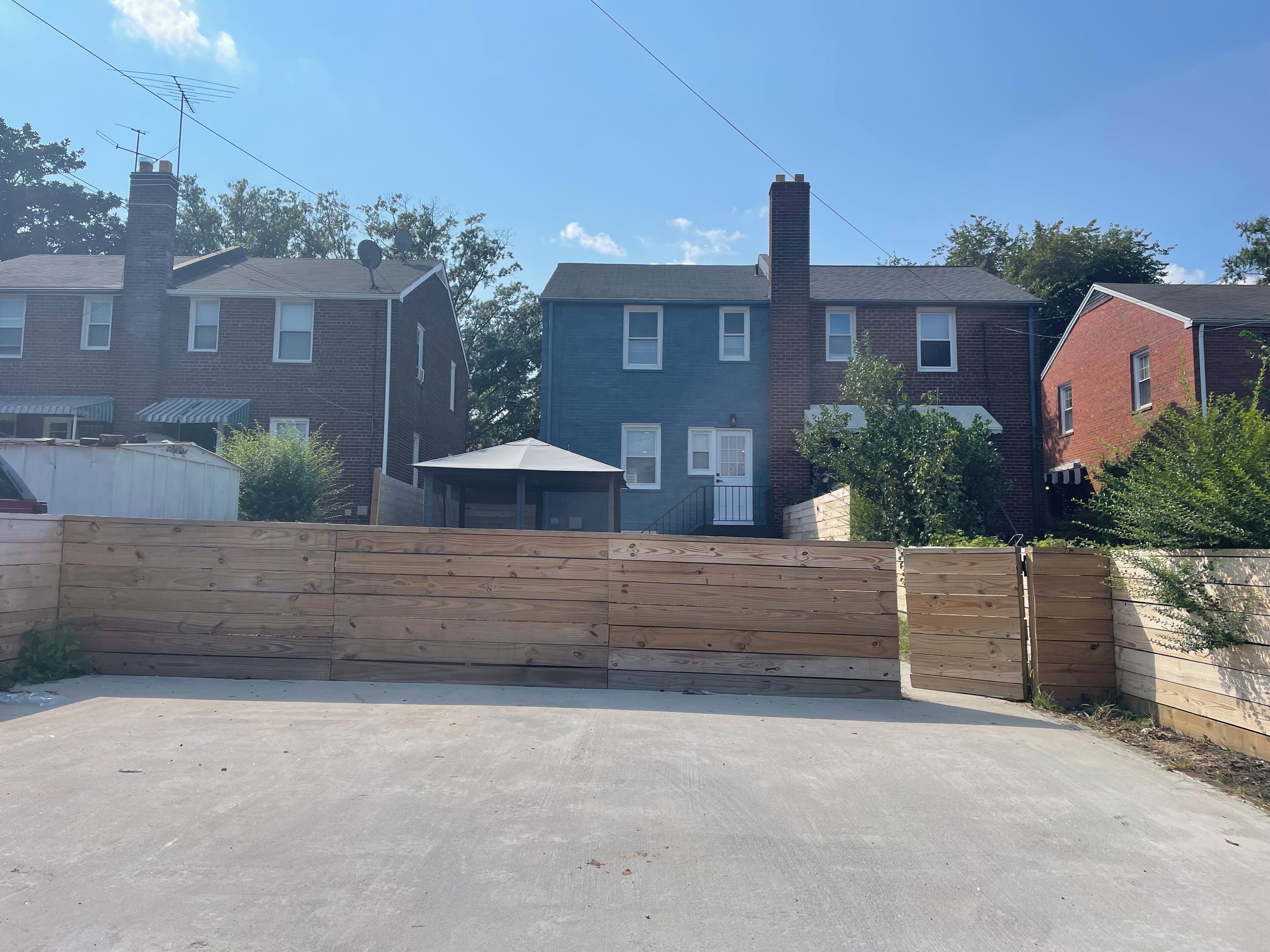 Un quartier résidentiel avec des maisons en briques, une allée en béton et une clôture en bois.
