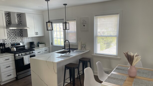 Una cocina moderna con armarios blancos, una isla central, taburetes de bar y una mesa de comedor con individuales.