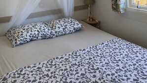 A bedroom with a bed, a canopy, a bedside lamp, and a window with curtains. - Cozy tiny house in nature, 5 mins from Beach | With sea view & high speed WiFi (Tarifa)