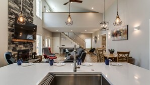 Une cuisine spacieuse avec un îlot central, une cheminée en pierre et des luminaires suspendus.
