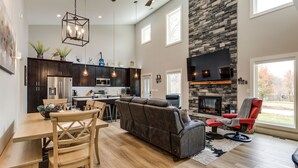 Un vaste espace de vie doté d’une cheminée en pierre, d’un canapé et d’une table à manger avec des chaises.