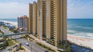 A high-rise hotel with multiple balconies, a beach view, and a pedestrian walkway. - Emerald Isle 506 - Beautiful beachfront condo! Front row chairs included! (Panama City Beach)