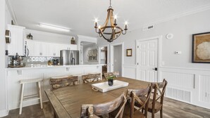 A spacious kitchen with white cabinetry, a wooden dining table, and a chandelier. - Emerald Isle 506 - Beautiful beachfront condo! Front row chairs included! (Panama City Beach)