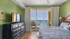 Habitación de hotel con cama, cómoda, televisor y vista al océano.