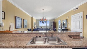 Cozinha com bancadas de granito, pias de aço inoxidável e um candelabro.