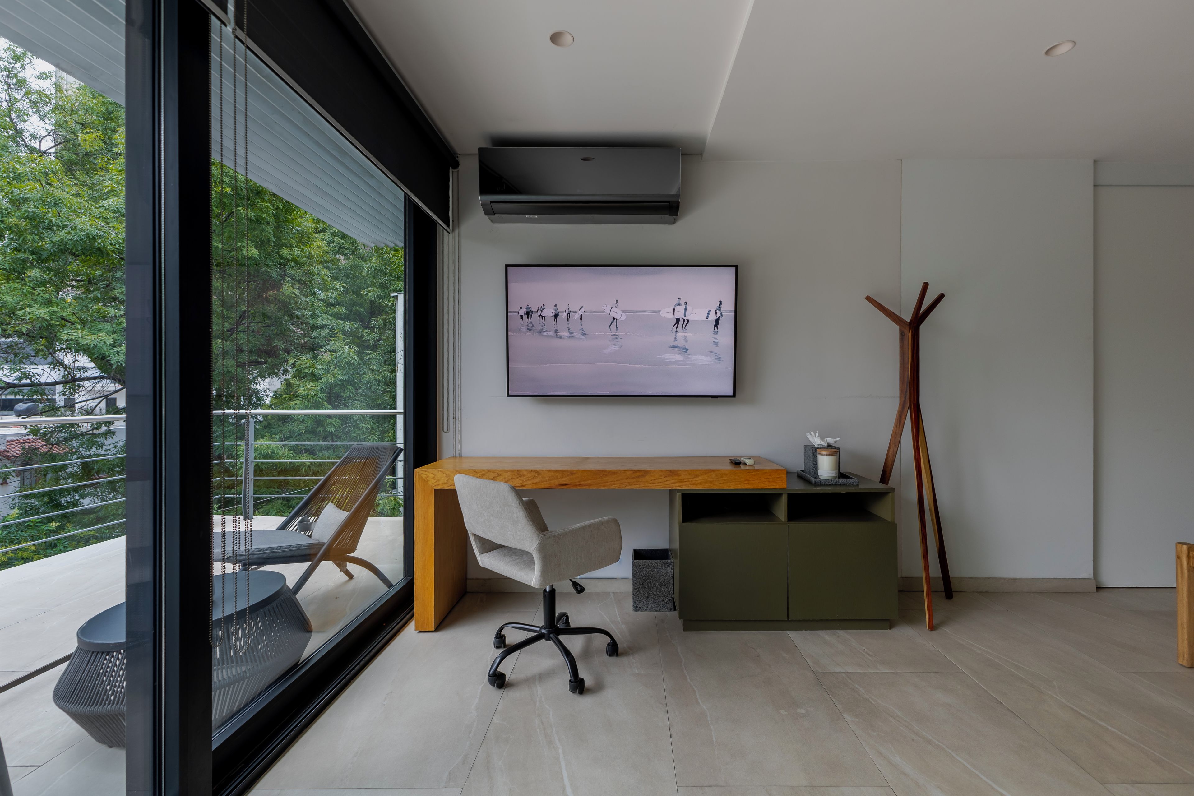 Un espacio de oficina moderno con un escritorio, una silla y un amplio ventanal con vistas a zonas verdes.