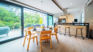 A modern kitchen with a large island, bar stools, and a dining area with a round table and chairs. - Capitalia Parque Lincoln (Mexico City)