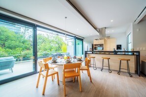 A modern kitchen with a large island, bar stools, and a dining area with a round table and chairs. - Capitalia Parque Lincoln (Mexico City)