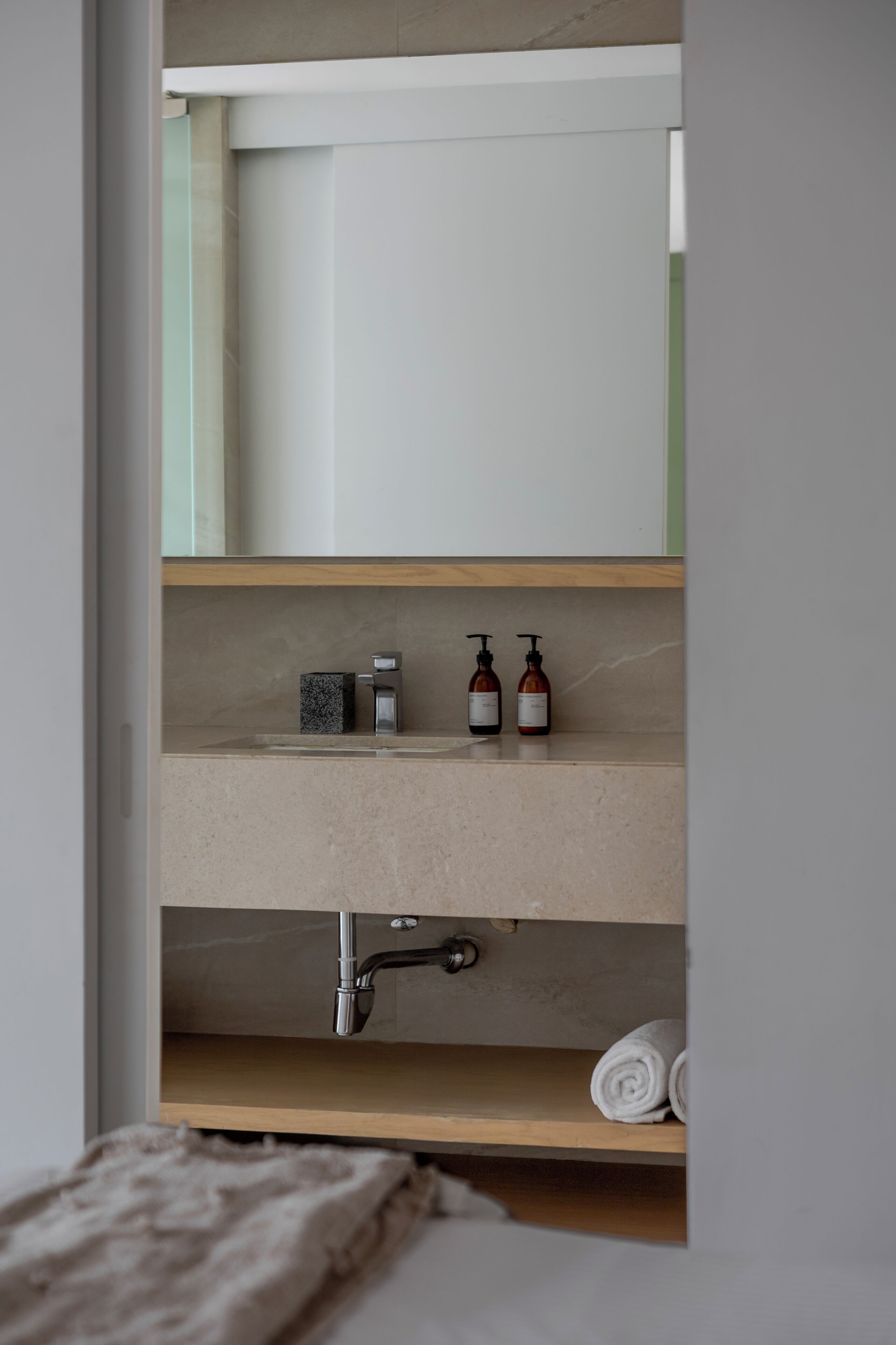 A bathroom with a built-in shelf, a sink, and a towel.
