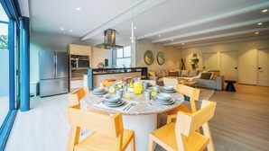 A modern kitchen with a central island, dining table with chairs, and a living area with a sofa and coffee table. - Capitalia Parque Lincoln (Mexico City)