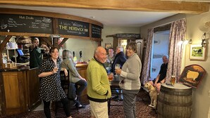 A cozy pub with a wooden interior, a bar area, and a dog on the floor. - Herdwick Inn (Penrith)