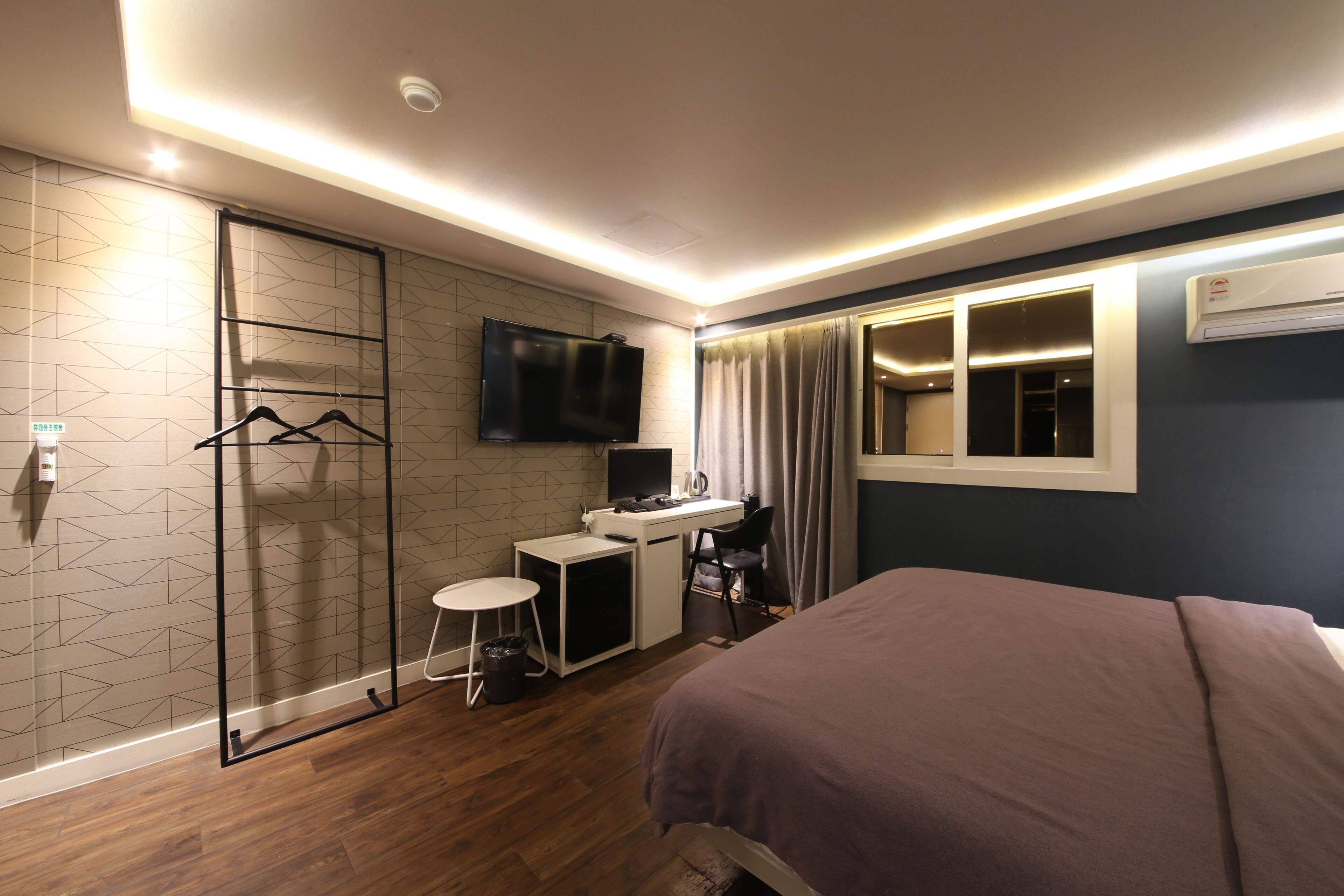 A modern hotel room with a bed, desk, and TV.