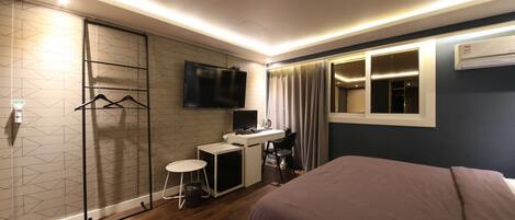 A modern hotel room with a bed, desk, and TV.