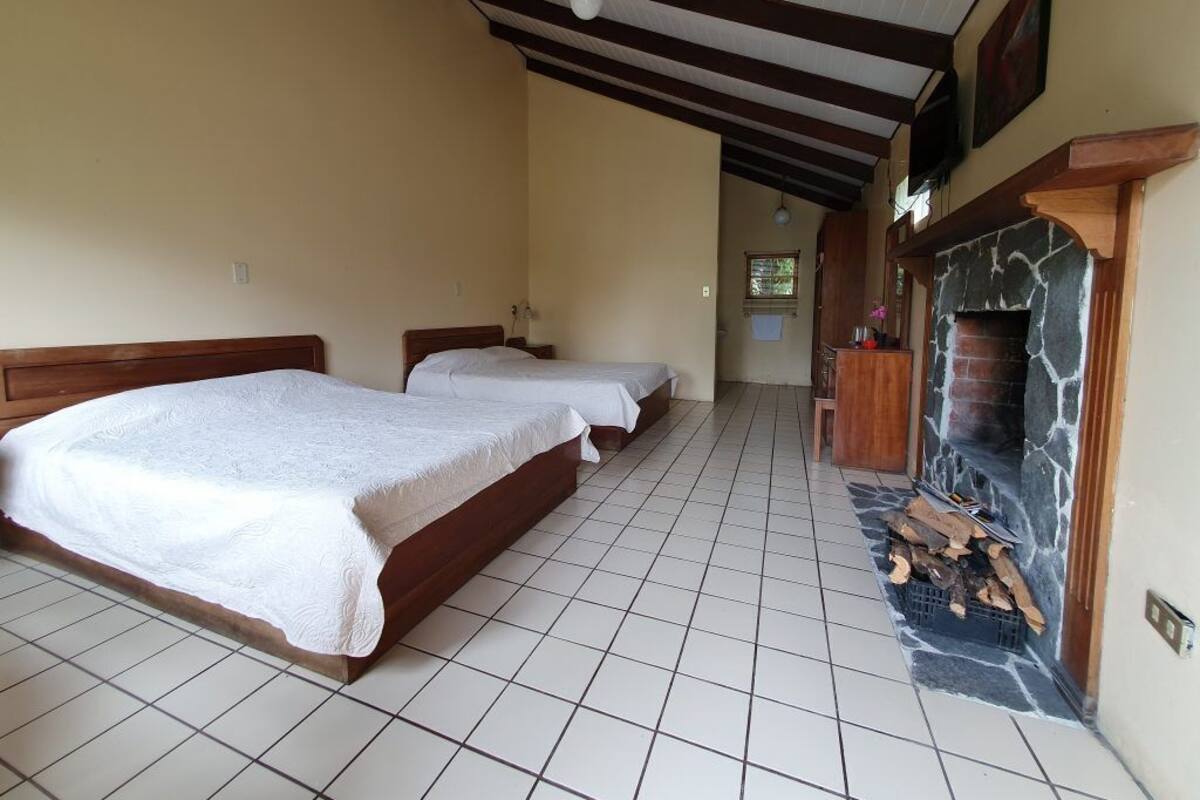 Un dormitorio con dos camas, una chimenea de piedra y piso de baldosas.