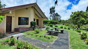 A house with a front porch, a stone pathway, and a garden with benches. - Hotel Villa Zurqui (San Jeronimo)