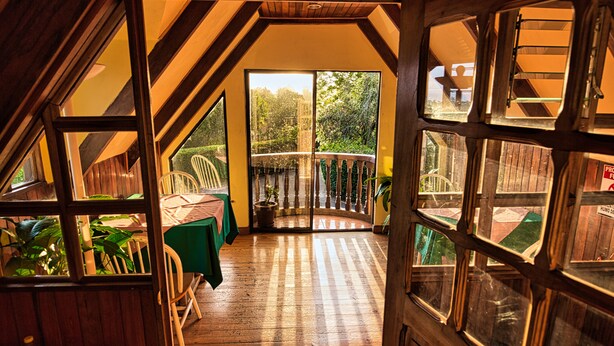 A wooden interior with a view of a garden through large windows. - Hotel Villa Zurqui (San Jeronimo)
