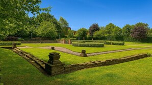 Ein gepflegter Garten mit Steinwegen und ordentlich geschnittenen Hecken.