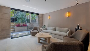 Una sala de estar moderna con un sofá, sillones, una mesa de centro y un ventanal con vistas a zonas verdes.
