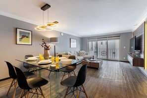 A modern living room with a glass dining table, black chairs, a sofa, and a large window. - Capitalia Obelisk Polanco (Mexico City)