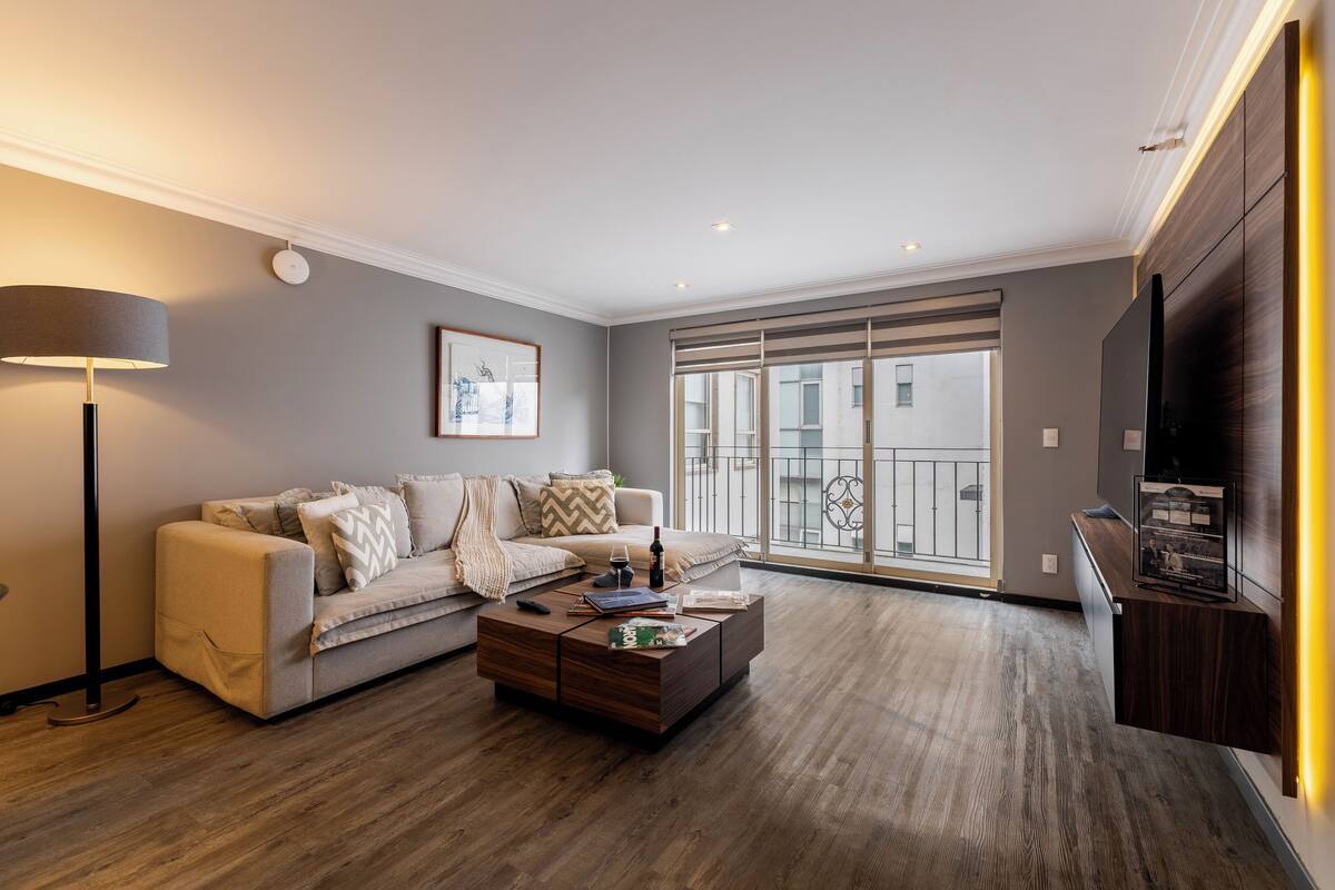 Una sala de estar moderna con sofá, mesa de centro y televisor.