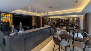 Zona de bar moderna con mostrador, asientos y una televisión.