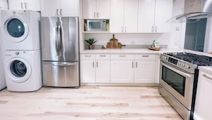 Een moderne keuken met roestvrijstalen apparatuur, witte kasten en een houten vloer.