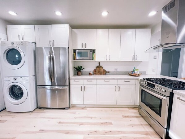 A modern kitchen with stainless steel appliances, white cabinets, and a wooden floor.