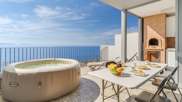 A balcony with a hot tub, outdoor table with food, and a brick oven. - Casa Morena by Atlantic Holiday (Santa Cruz)