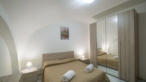 Quarto moderno com uma cama grande, mesa de cabeceira, abajur, guarda-roupa e um quadro na parede.