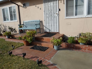 A house with a number 423 sign, a blue bench, and potted plants.