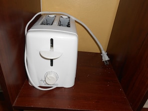 A white toaster with a power cord on a wooden surface.