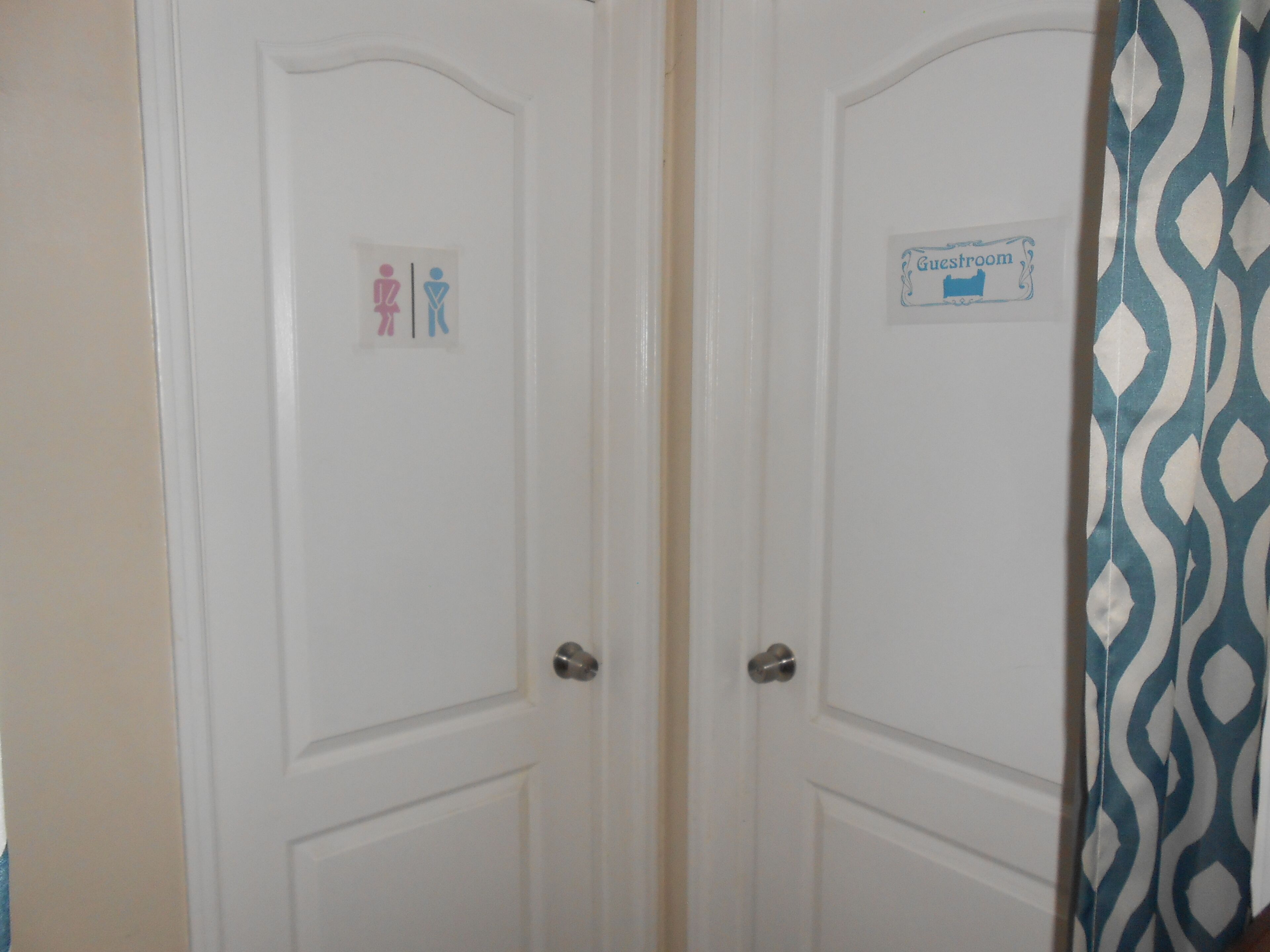 Un conjunto de puertas blancas con un letrero de baño y un letrero de habitación de huéspedes.