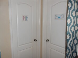 Een aantal witte deuren, een bordje ‘toilet’ en een bordje ‘logies’.