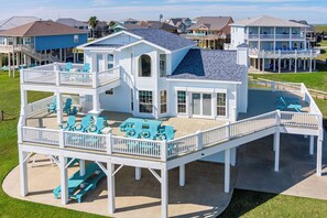 Une maison de deux étages située en bord de mer, dotée d’une terrasse, d’un espace salon extérieur et d’un toboggan.
