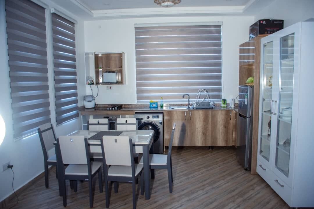 A compact kitchen with a dining area, built-in appliances, and a glass-fronted cabinet.