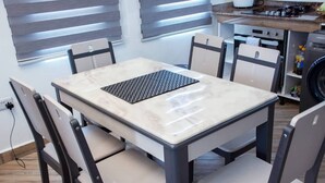 Un coin repas avec une table en marbre, quatre chaises et une cuisine en arrière-plan.