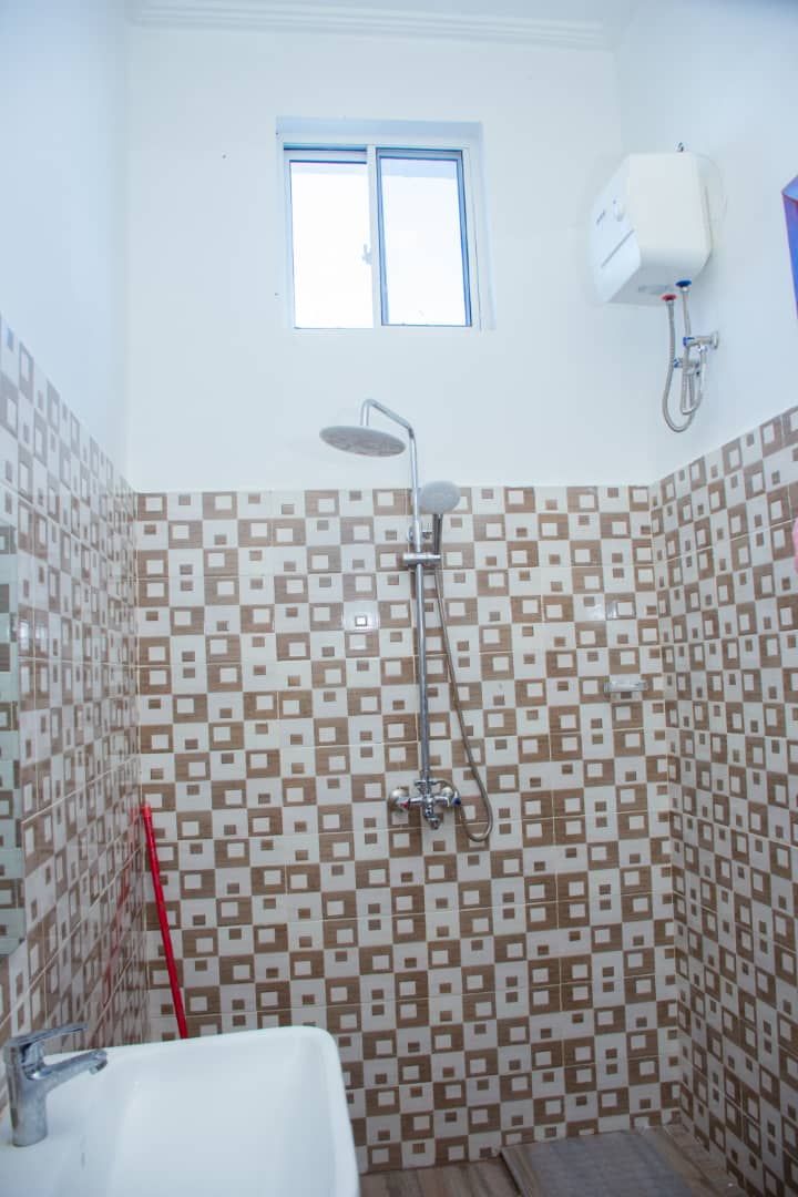 Un baño con ducha, lavamanos y ventana.