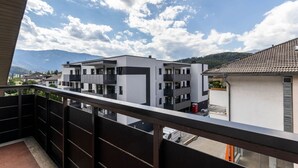 Un immeuble d’appartements moderne doté de balcons, avec un ciel dégagé et des montagnes en arrière-plan.