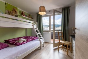Een kamer met stapelbedden, een bureau, een stoel en een raam met gordijnen.