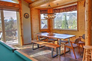 A wooden cabin interior with a dining table, benches, and a chandelier.