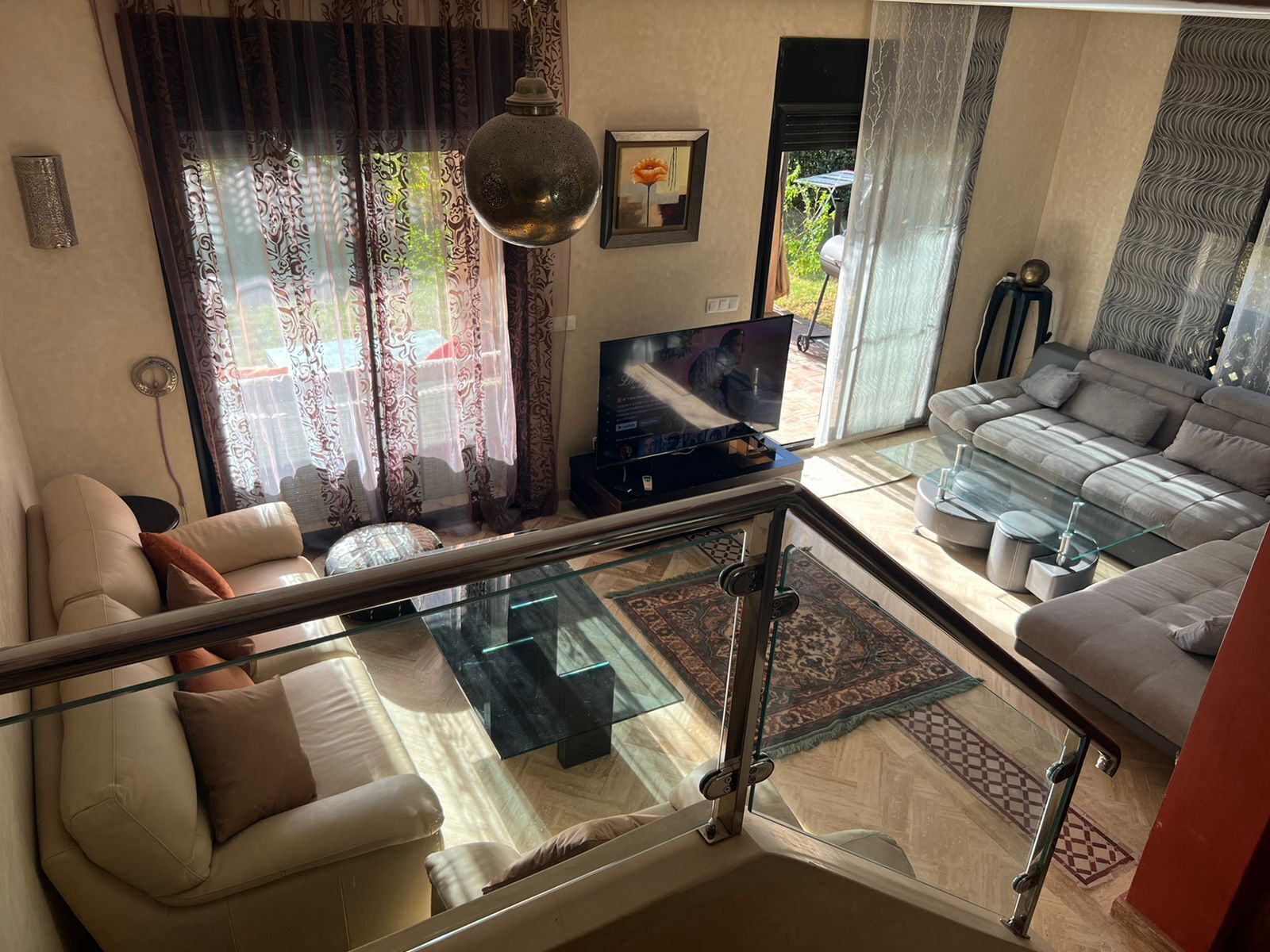 A living room with a sofa, a glass coffee table, and a television.