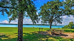 A park with a picnic table and benches, surrounded by trees and a lake. - Best kitchen in Texoma! New! Playroom! (Mead)