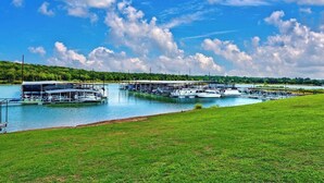 A marina with boats docked, a grassy area in the foreground, and a bridge in the background. - Best kitchen in Texoma! New! Playroom! (Mead)
